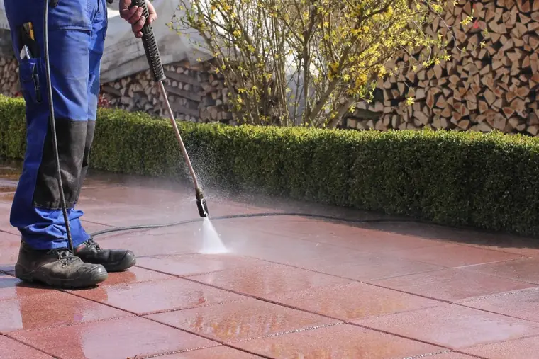Nettoyage d'une terrasse dallée au nettoyeur haute pression, lance en action